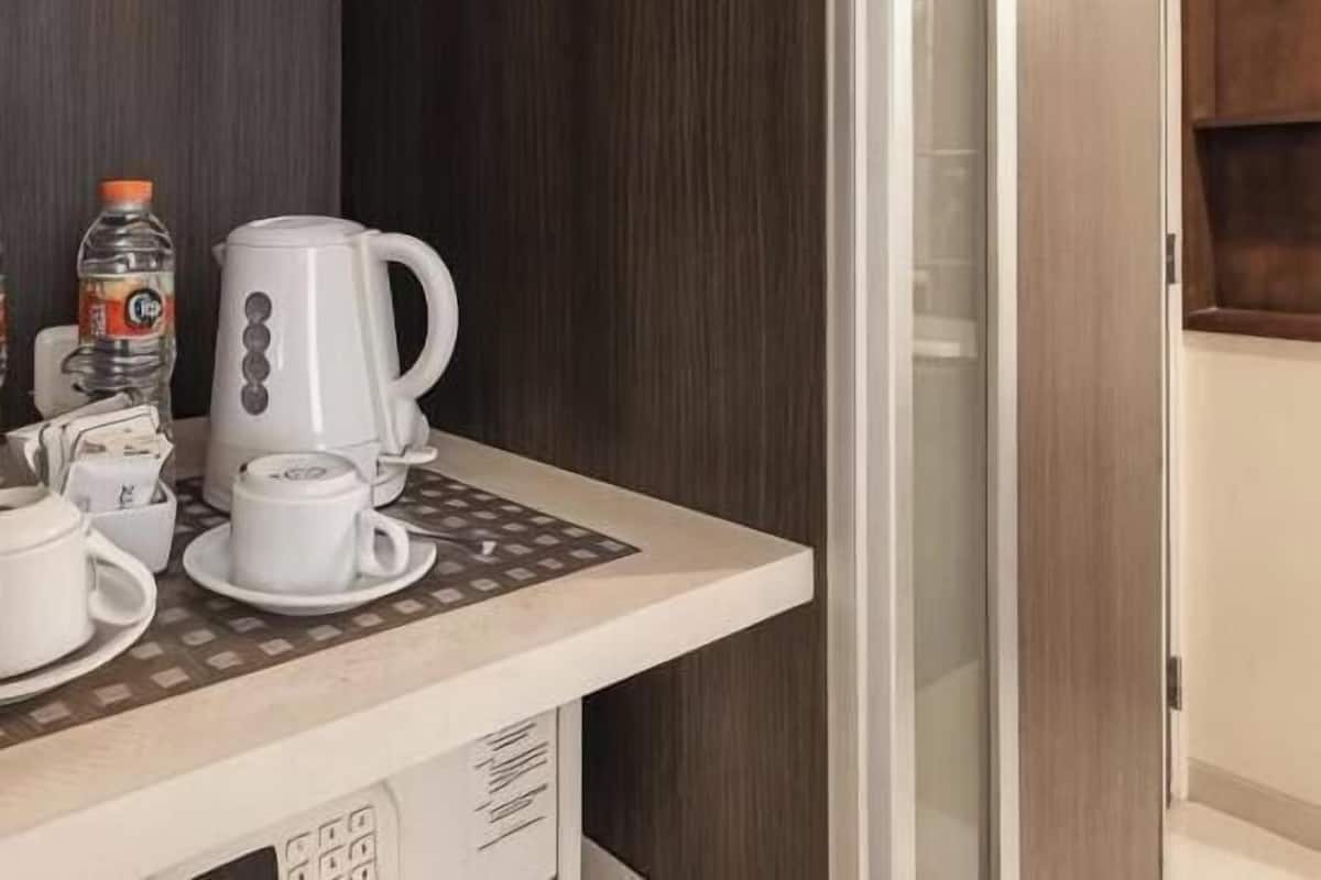 A kitchenette with a coffee maker, a kettle, a water bottle, and a cup on the counter.