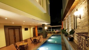 Zona de piscina interior con comedor y detalles de pared de piedra.