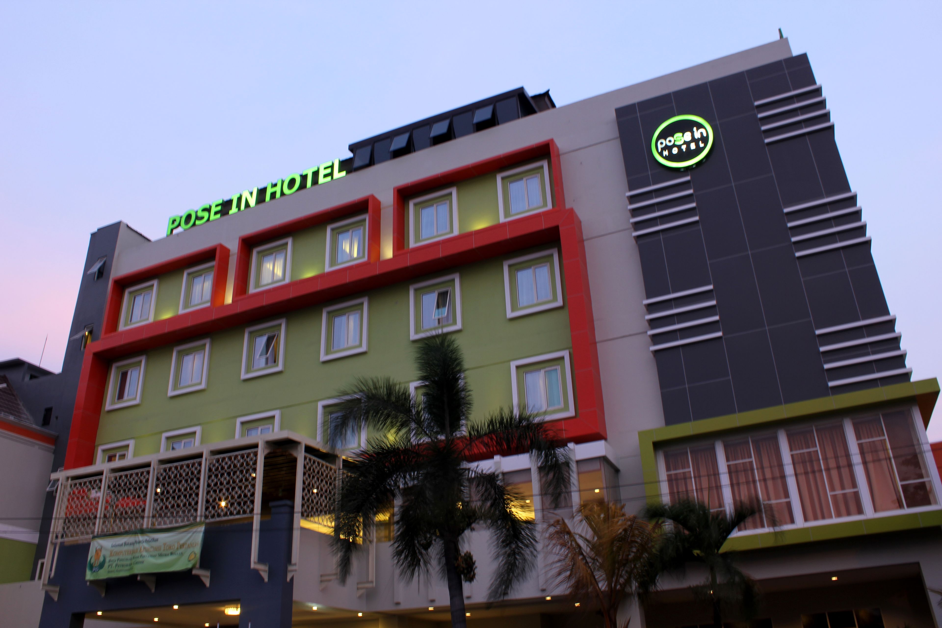 A hotel with a green and red facade, multiple windows, and a sign that reads "POSE IN HOTEL".