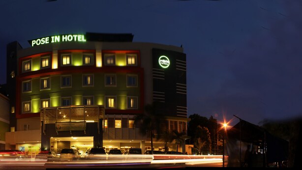 Un hotel con un letrero llamativo que dice "POSE IN HOTEL" y un cajero automático visible en la planta baja.