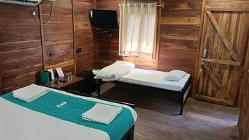 Una habitación estilo cabaña de madera con dos camas, un televisor y una ventana con cortinas.
