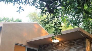 A modern outdoor area with a pool, two white folding chairs, and a stone wall.