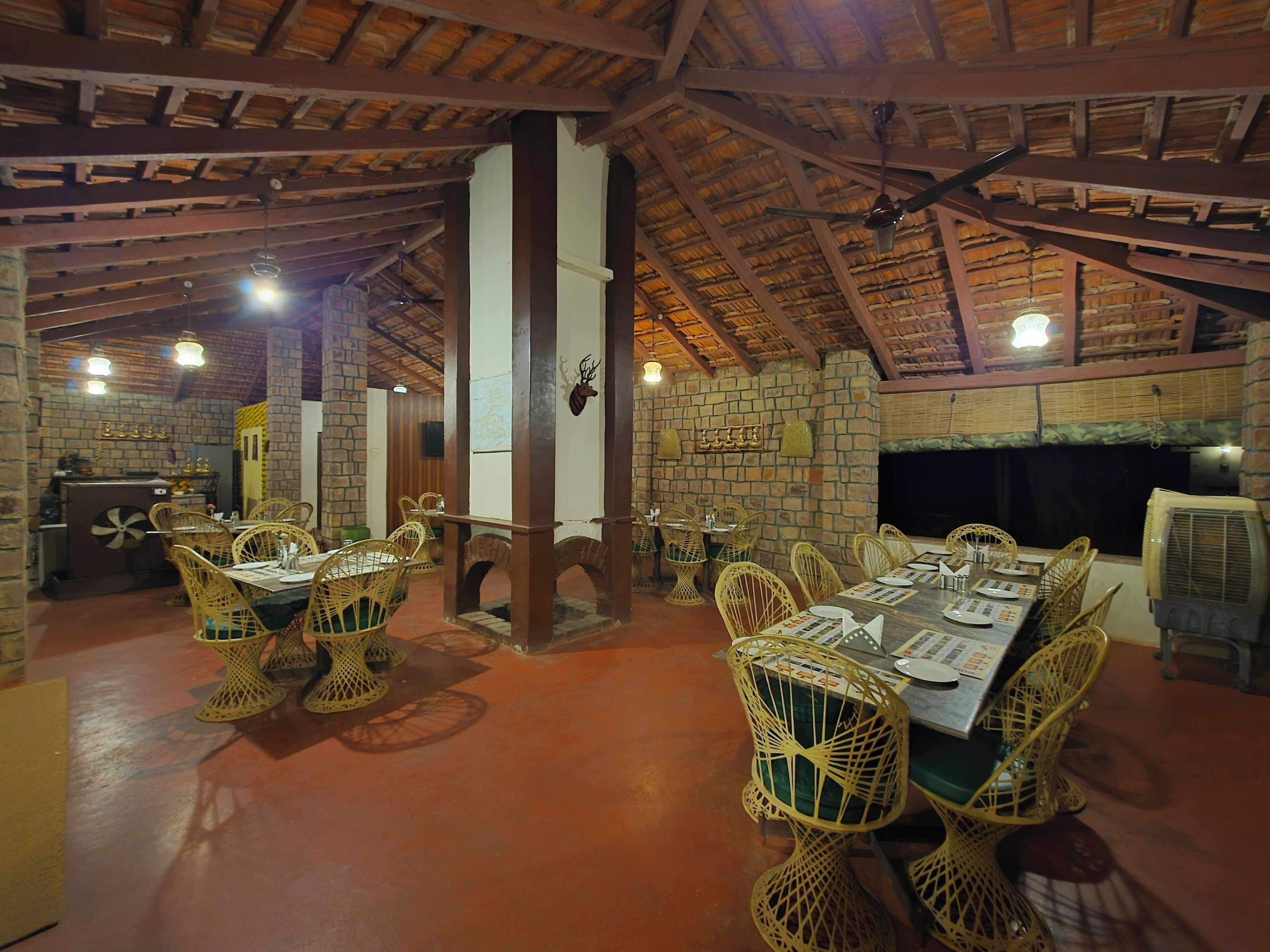 Un restaurante con paredes de piedra, vigas de madera y sillas de mimbre.