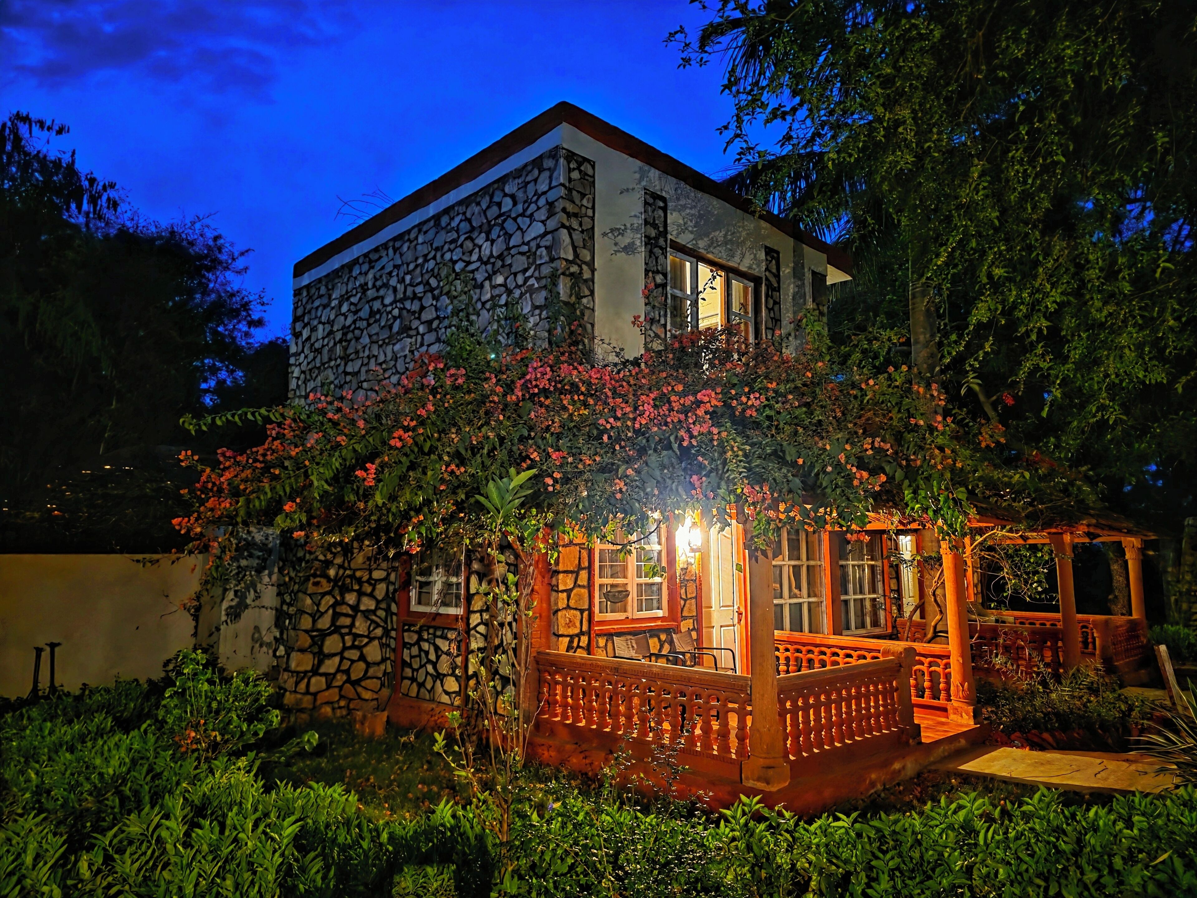 A stone building with a balcony and a garden at dusk.