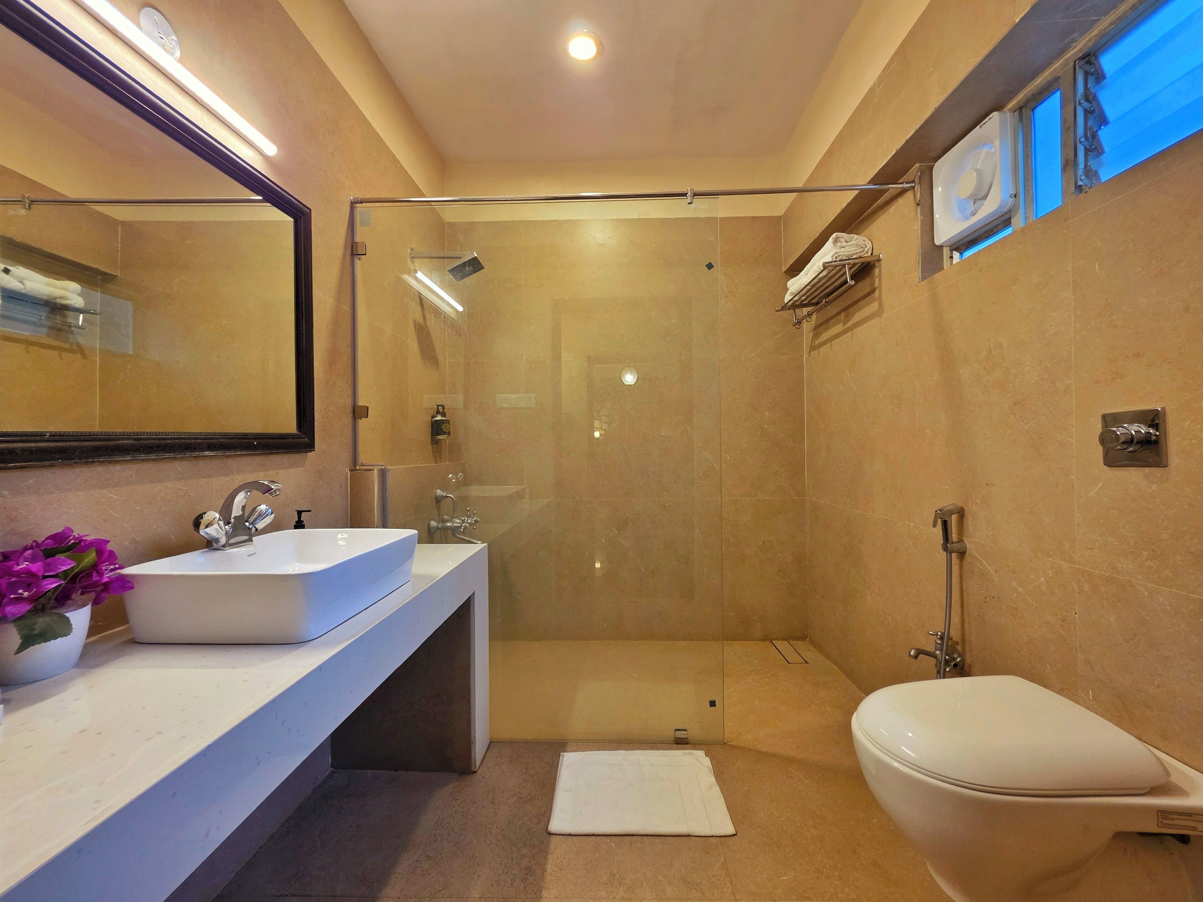 A modern bathroom with a glass-enclosed shower, a white sink, and a toilet.