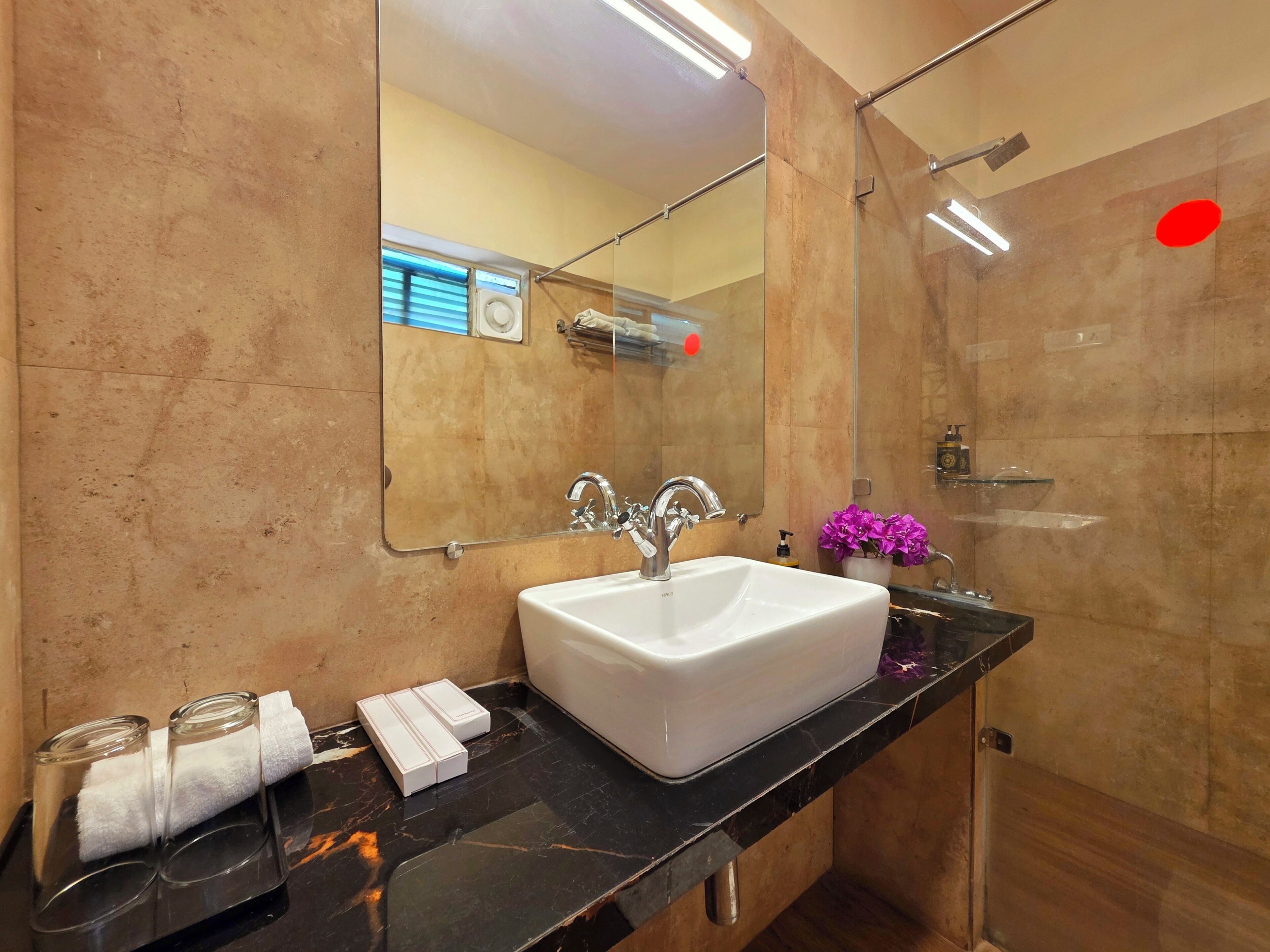 A bathroom with a white sink, a mirror, a glass shower enclosure, and a marble countertop.