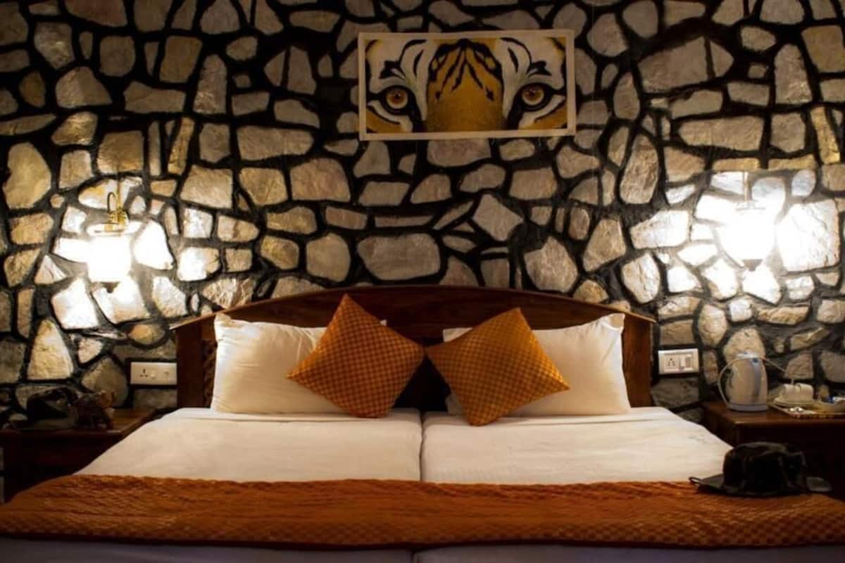 Een bed met een houten hoofdeinde, twee kussens, een stenen muur en een tijgerprint erboven.