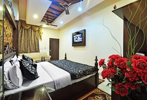 A bedroom with a bed, a television, and a decorative mirror.