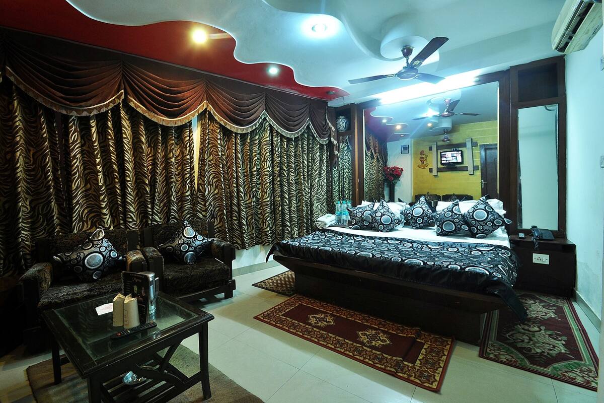 A bedroom with a large bed, a sofa, a coffee table, and curtains.