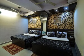 Habitación de hotel con dos camas, ventilador de techo y diseños decorativos en las paredes.