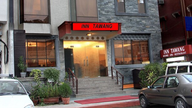 Un immeuble à plusieurs étages, sur lequel on peut lire l’inscription « INN TAWANG », ce qui indique qu’il s’agit d’un hôtel.