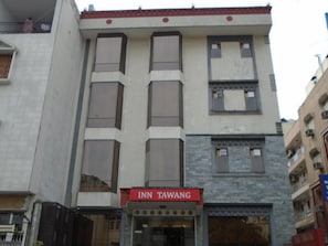 Un bâtiment avec une enseigne indiquant « INN TAWANG » au niveau du rez-de-chaussée.