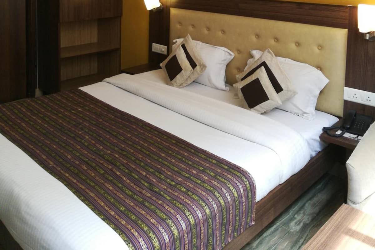 A hotel room with a bed, a wardrobe, a nightstand, and a wall-mounted picture.