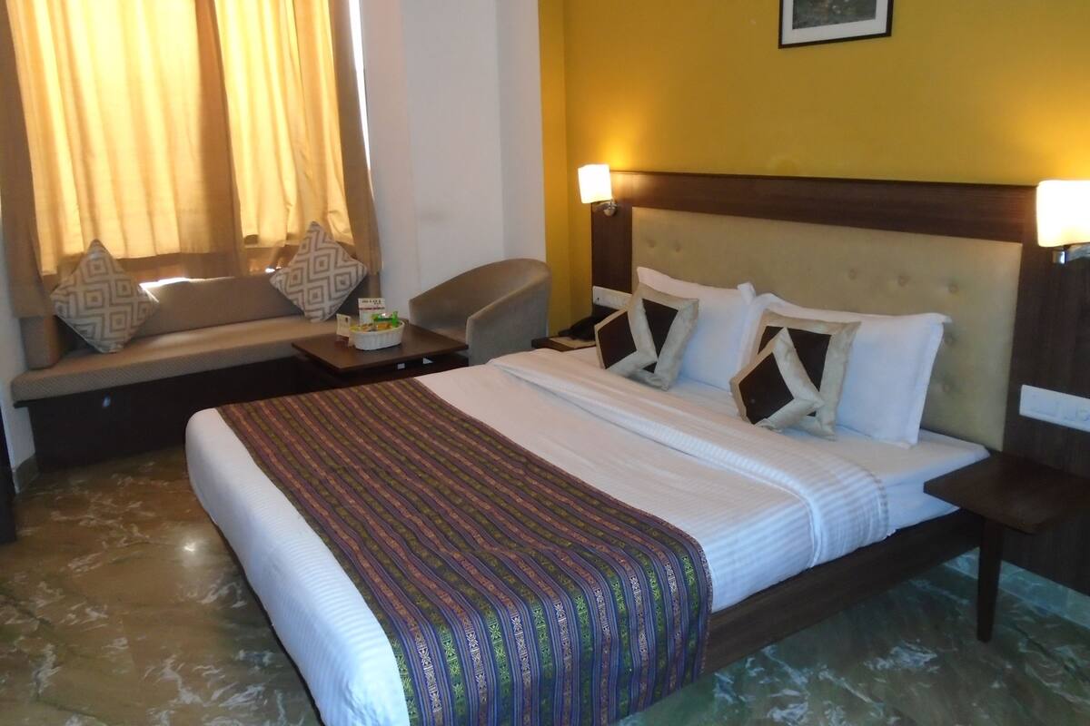 A hotel room with a bed, a sofa, a chair, and a nightstand.