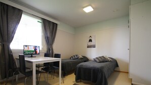 Een kamer met twee eenpersoonsbedden, een bureau met een computer en een stoel.