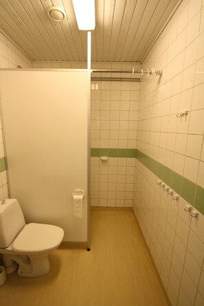 A small, tiled bathroom with a toilet, a shower stall, and a towel rack. - Forenom Hostel Kuusamo (Kuusamo)