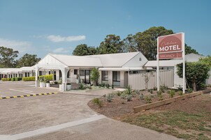 A motel with a sign indicating vacancy, a parking lot, and a landscaped area with plants.