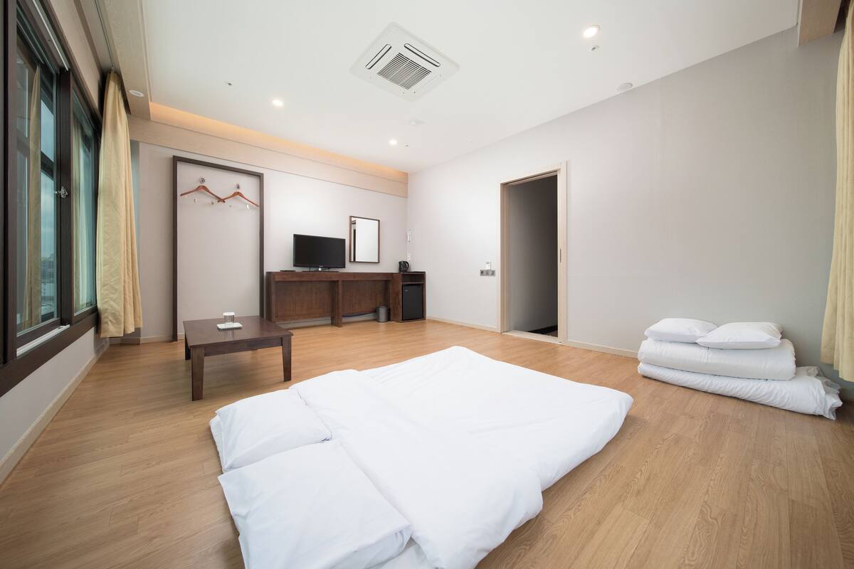 Una habitación de hotel moderna con una cama grande, un escritorio, un televisor y un armario.