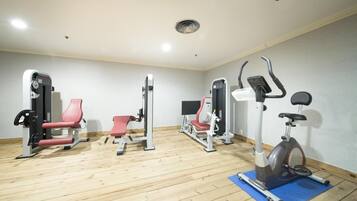 A gym with various exercise equipment, including a bench press, a leg press, a chest press, and an elliptical machine.
