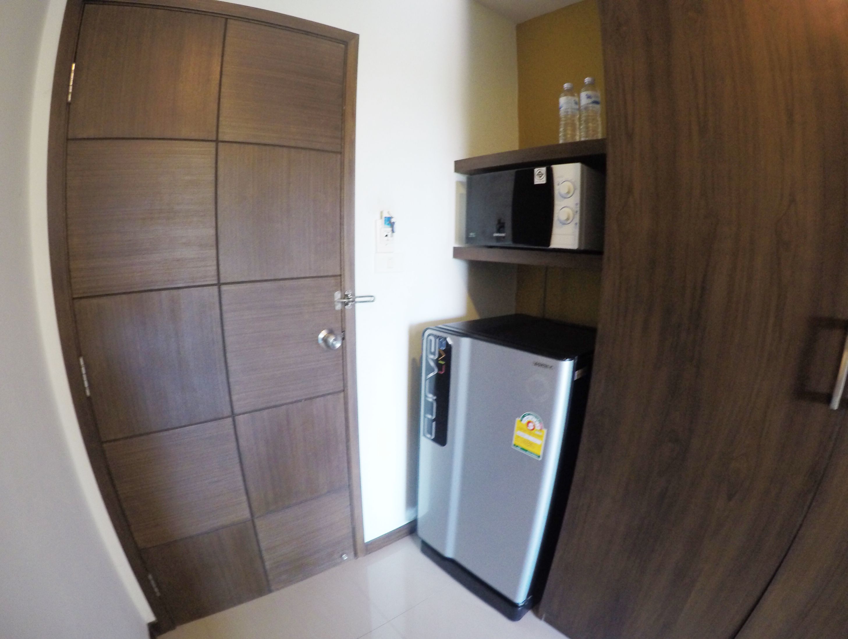 A compact kitchen with a refrigerator, microwave, and wooden cabinet.