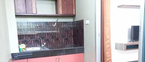 A compact kitchen with a sink, cabinets, and a dining area with a bench.