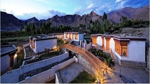 Un hotel con varias edificaciones conectadas por un puente, con montañas al fondo.