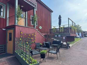 Ein rotes Gebäude mit Außenplätzen und einer Treppe, die zu einem Balkon führt.