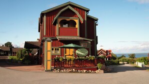 Un bâtiment à deux étages avec une façade rouge et jaune, un balcon orné d’un parasol vert et une enseigne indiquant qu’il s’agit d’un hôtel.