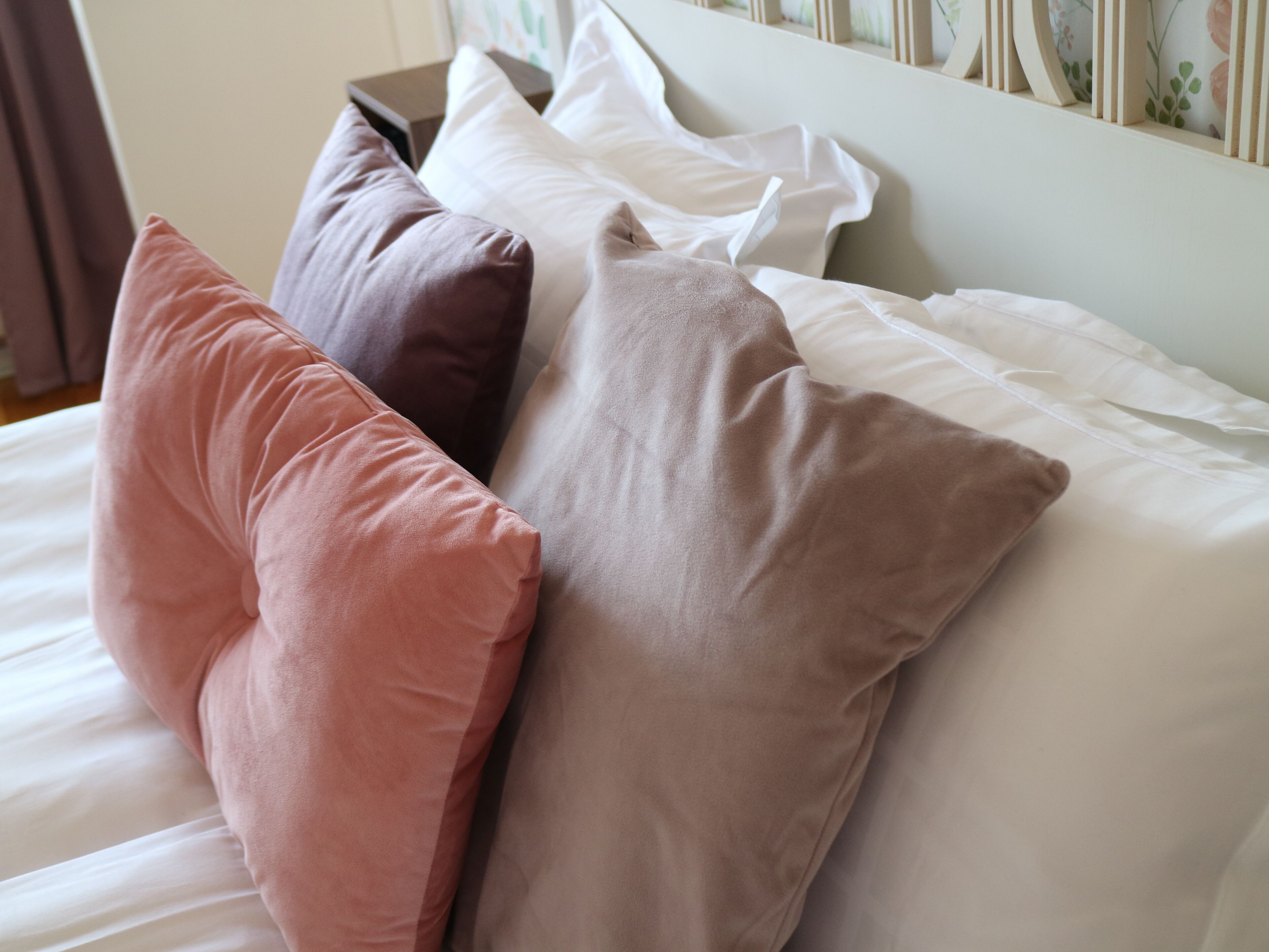 A bed with multiple pillows in various colors.