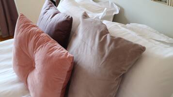 A bed with multiple pillows in various colors.