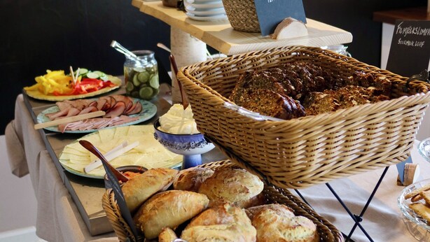 Une table de buffet proposant divers plats, notamment du pain, des pâtisseries, et agrémentée d’une décoration à motifs de tournesols.
