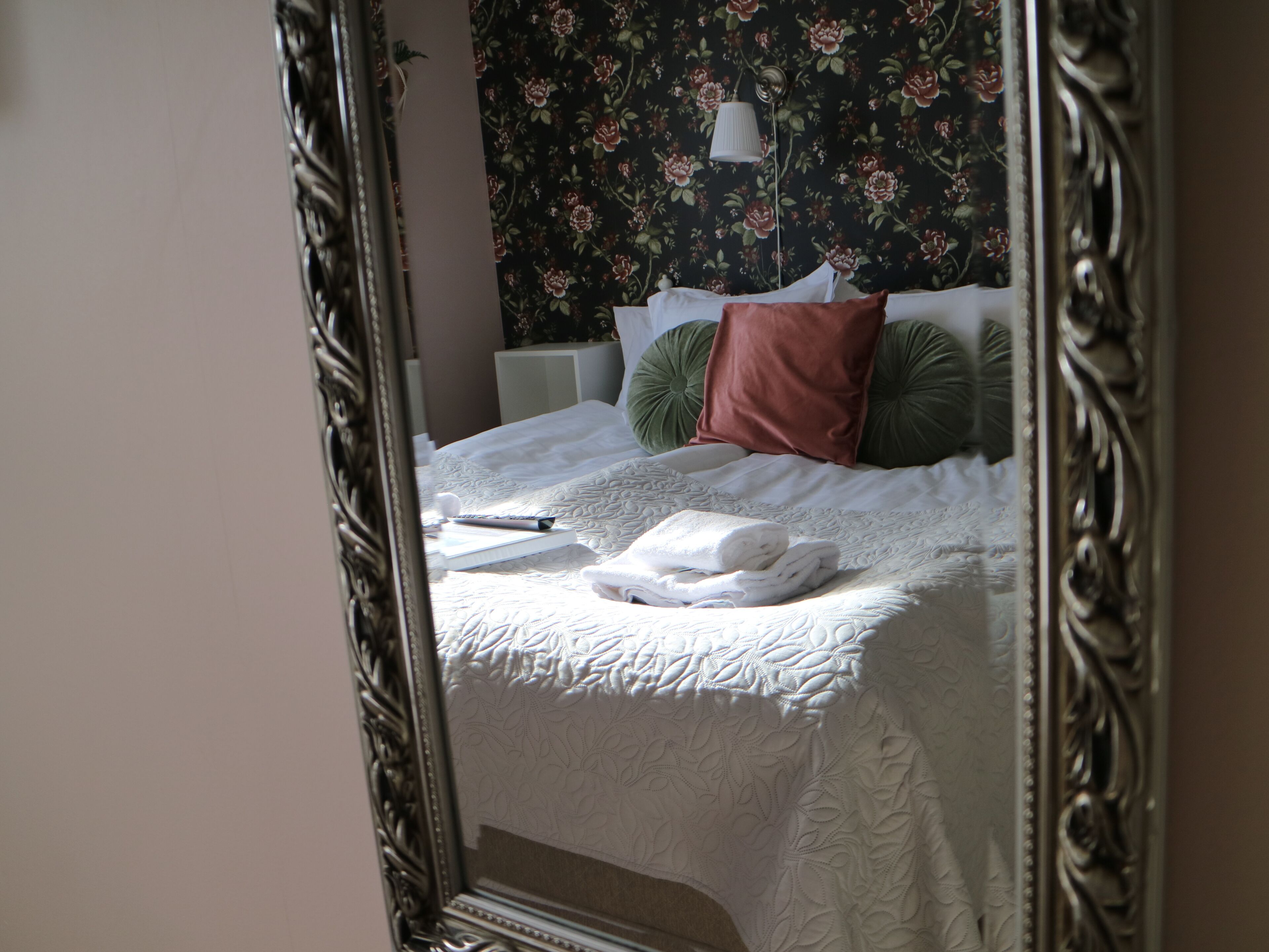 A neatly made bed with a white duvet, a green pillow, and a brown pillow.