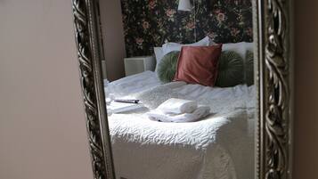 A neatly made bed with a white duvet, a green pillow, and a brown pillow.
