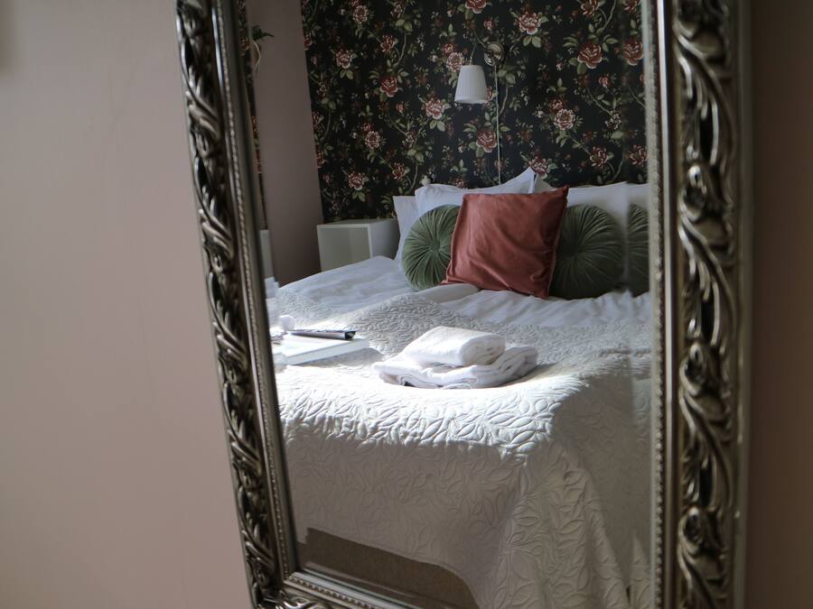 A neatly made bed with a white duvet, a green pillow, and a brown pillow.