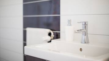 A modern bathroom with a white sink, chrome faucet, and a toilet.
