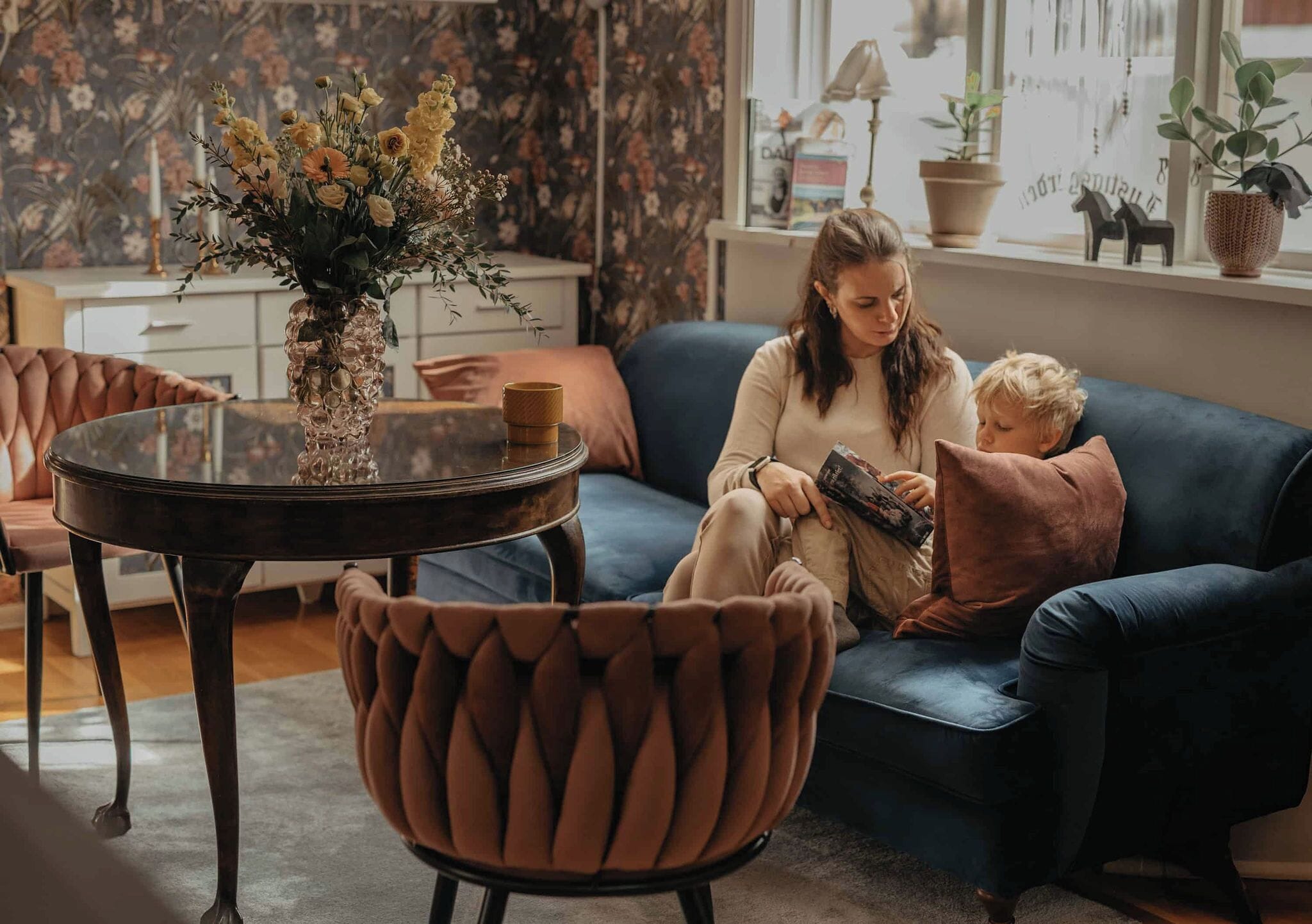 A living room with a sofa, a coffee table, and a decorative vase with flowers.