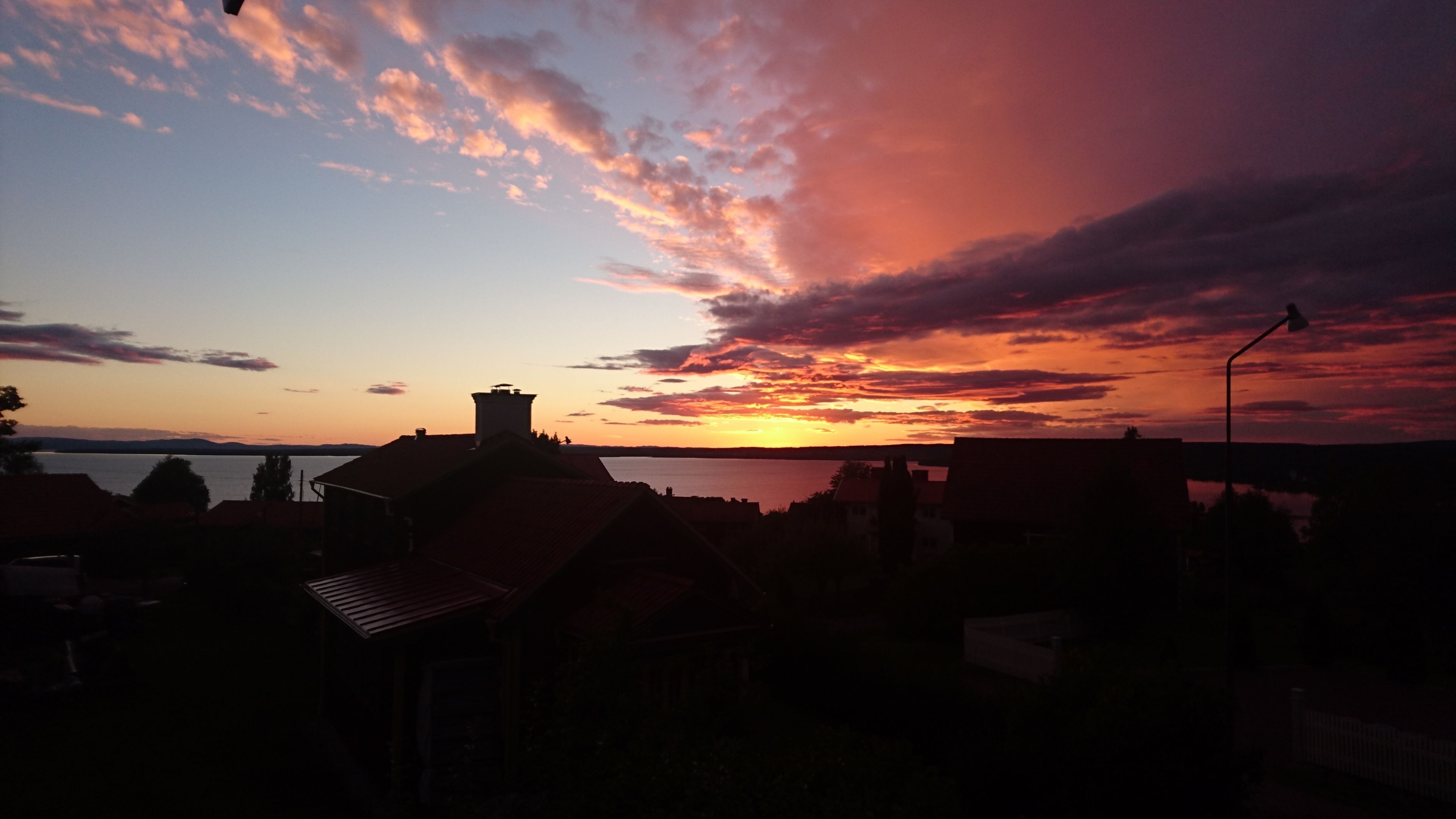 A sunset over a body of water with buildings silhouetted against the sky.