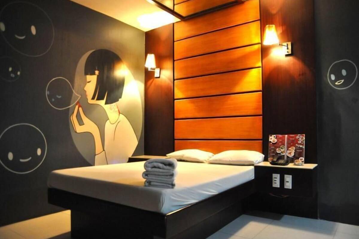 Een moderne hotelkamer met een bed, een nachtkastje en een muur met een groot cartoonesk personage.