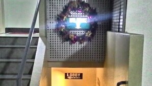 Een hal met een trap, een prullenbak en een bordje dat de hal aangeeft.