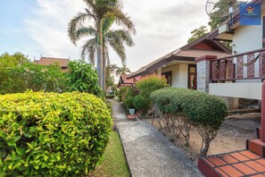 A pathway leading to a building with a tiled roof, surrounded by well-maintained greenery and a palm tree. - Starlight Haad Rin Resort (Ko Pha-ngan)