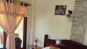 Un llit ben fet amb un capçal de fusta, un ram de flors i un quadre a la paret.