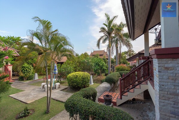 A courtyard with palm trees, a staircase, and a building with a tiled roof. - Starlight Haad Rin Resort (Ko Pha-ngan)