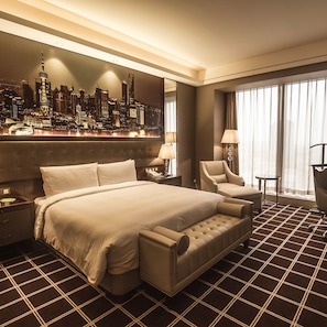 Habitación de hotel con una cama grande, vista panorámica de la ciudad, zona de bar y espacio para sentarse.
