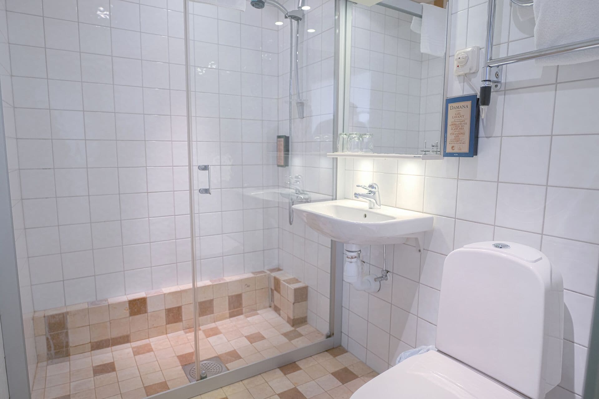 Egy fürdőszoba zuhanyzóval, mosdókagylóval és WC-vel.