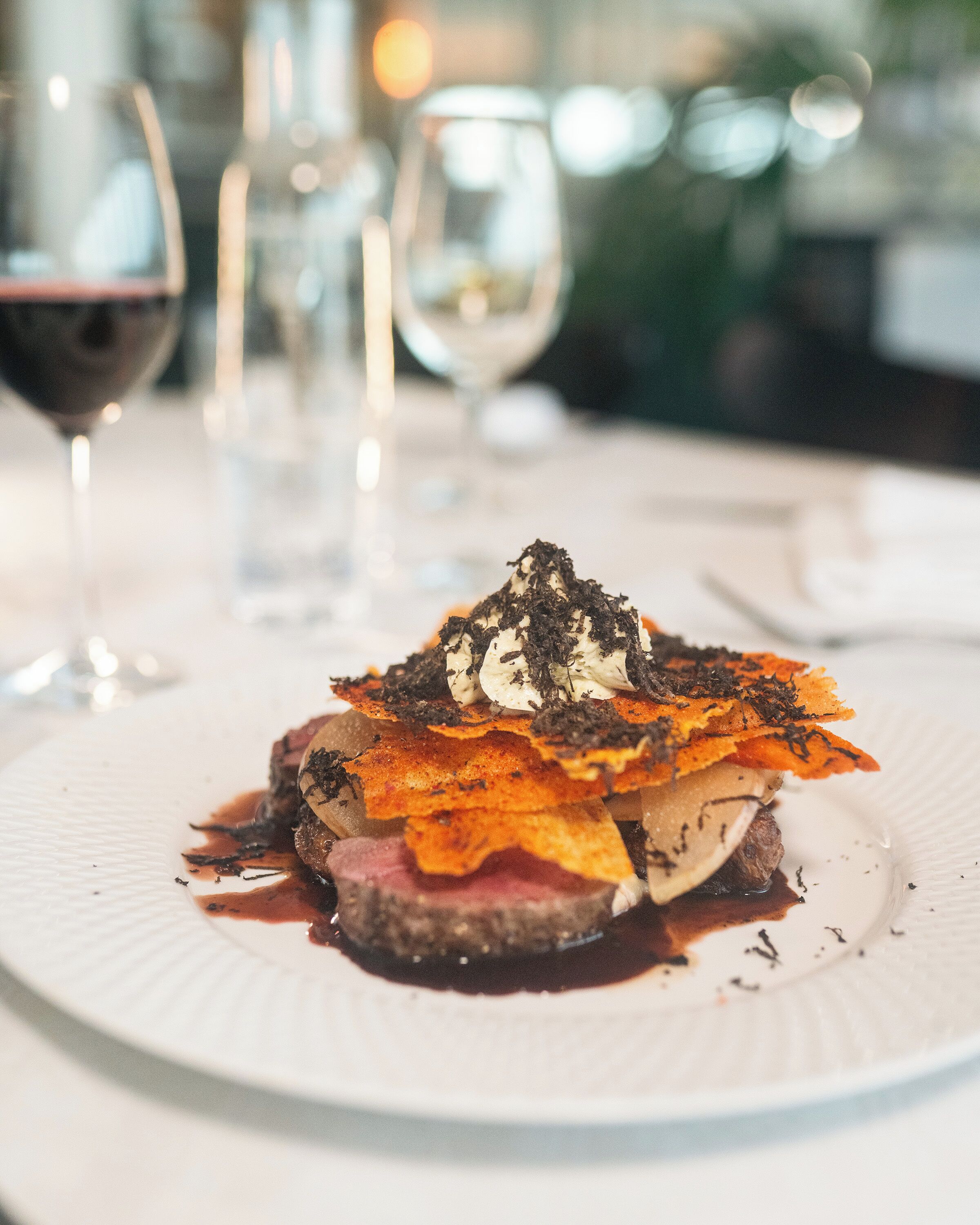 A plated dish with a steak, a slice of cheese, and a garnish on a white plate.