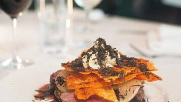 A plated dish with a steak, a slice of cheese, and a garnish on a white plate.