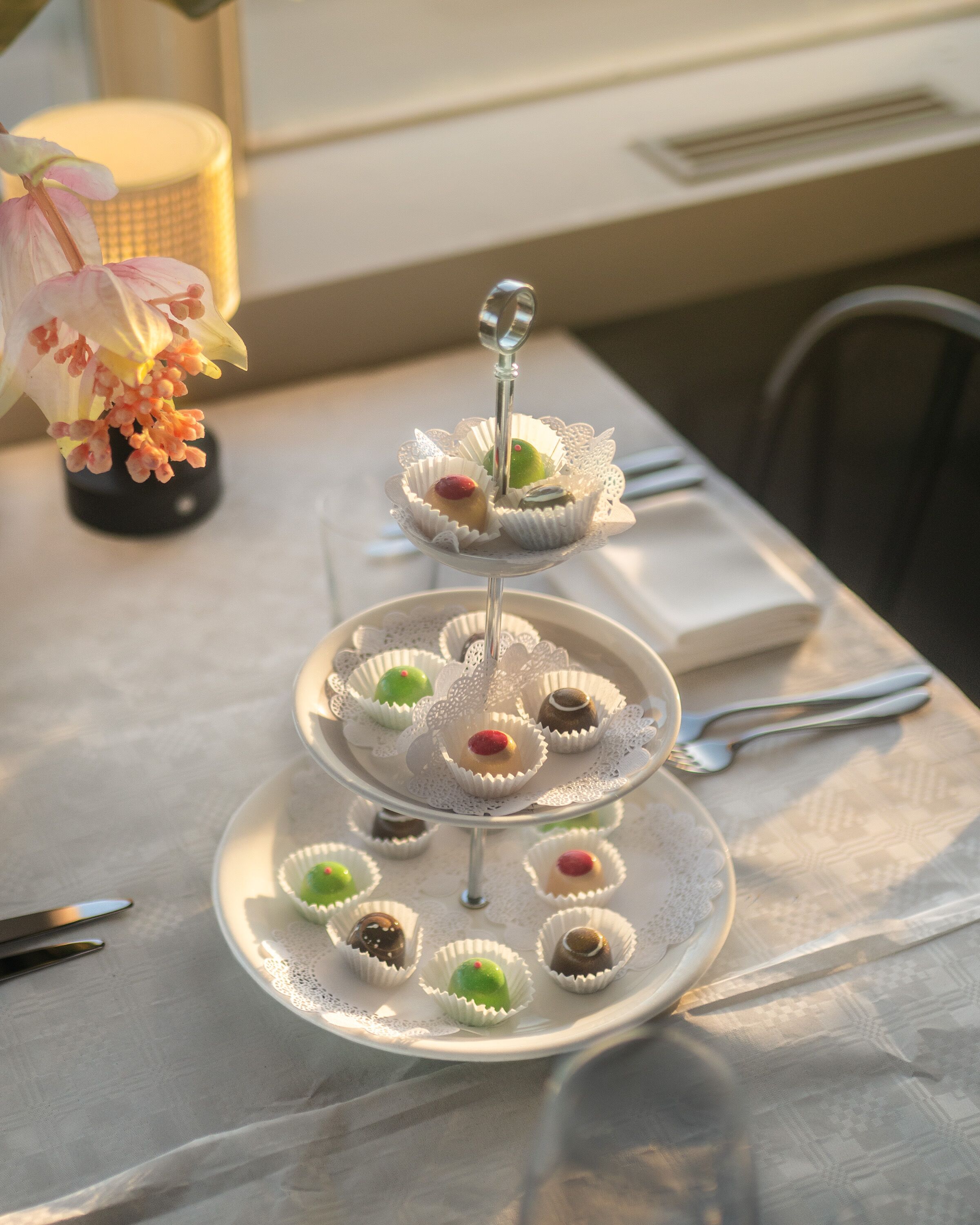A three-tiered dessert stand with various sweets on a table.