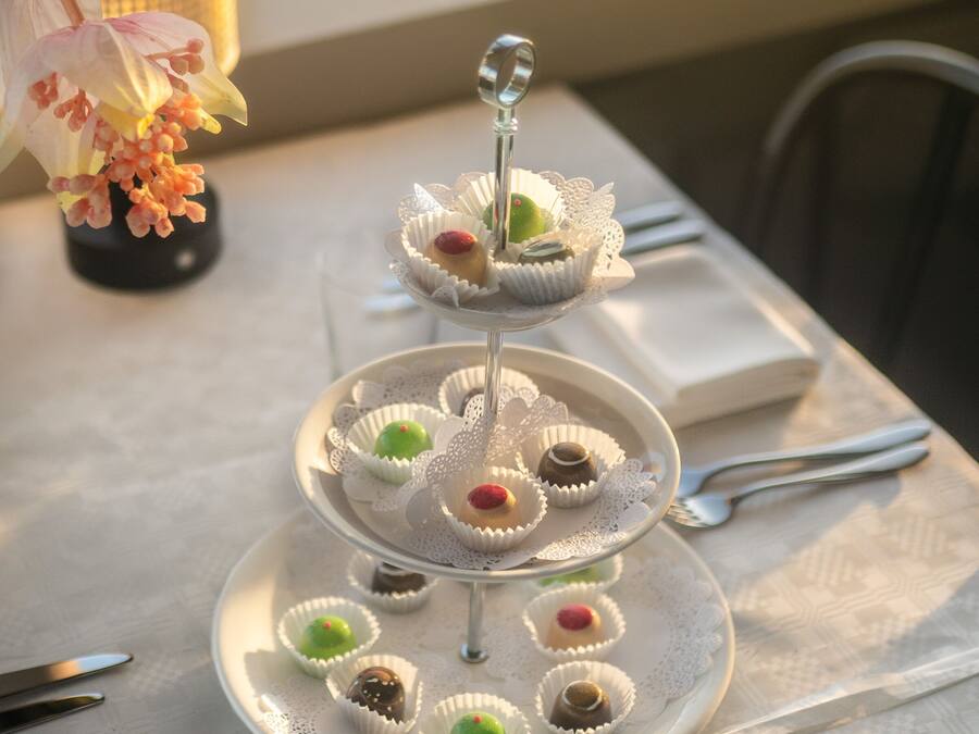 Un présentoir à trois niveaux, garni de diverses sortes de friandises, est posé sur une table.