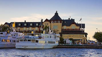 A waterfront with several boats docked, a building with a tower, and a flag.