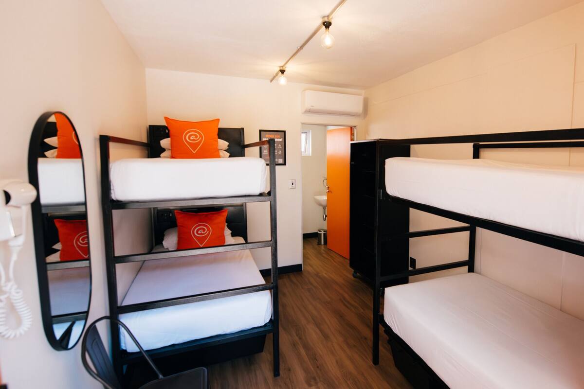 A bunk bed room with a telephone, a sink, and an air conditioning unit.